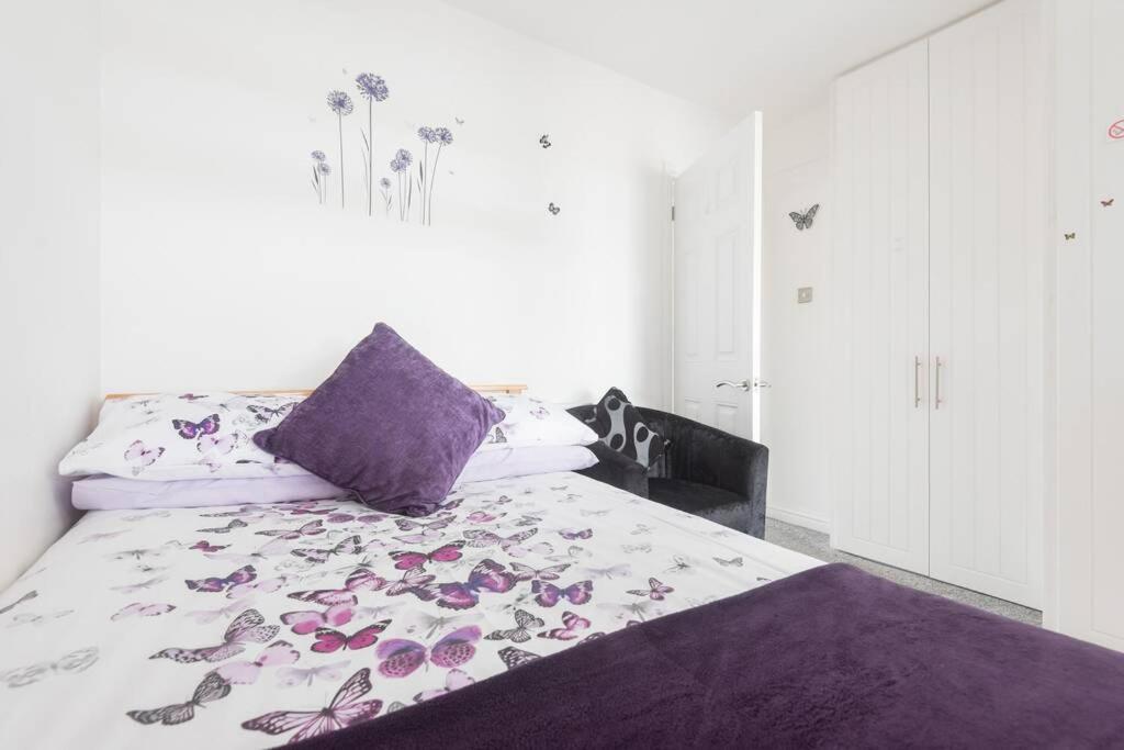 a bedroom with a bed with a purple pillow and flowers at Mayberry Lodge in Selsey