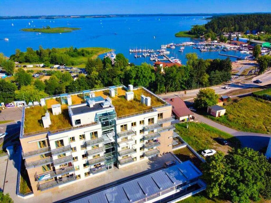 an apartment building with grass on its roof next to the water at Apartament AHOJ!!- Giżycko/ Wilkasy in Wilkasy