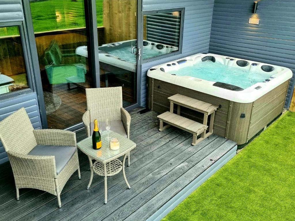 Carr的住宿－Yaseva Lodge, Stylish Country Retreat for 2, Hot Tub, Exceptional Views!，甲板上的热水浴池配有桌椅