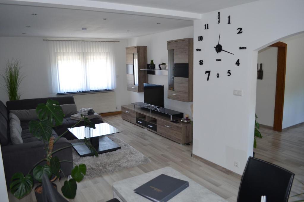 a living room with a couch and a clock on the wall at Ferienwohnung Stambach in Contwig