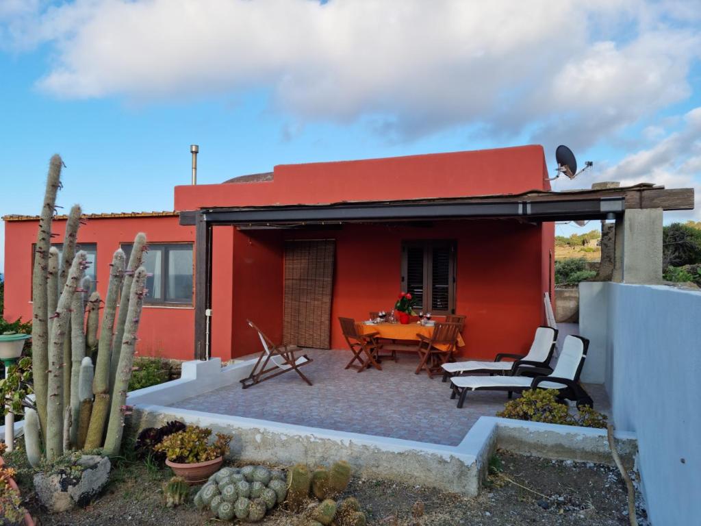 une maison rouge avec une table et des chaises dans l'établissement Dammuso "il cactus", à Pantelleria