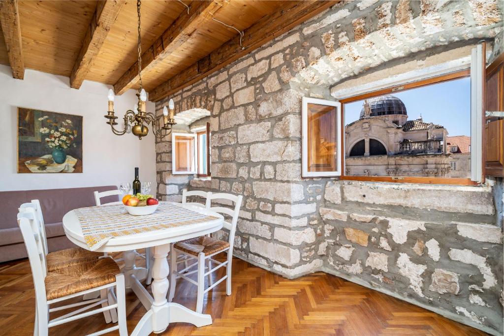 a room with a table and chairs and a brick wall at Apartments Martecchini in Dubrovnik