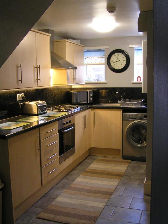 a kitchen with white cabinets and a clock on the wall at 2 Beach House in Bridlington