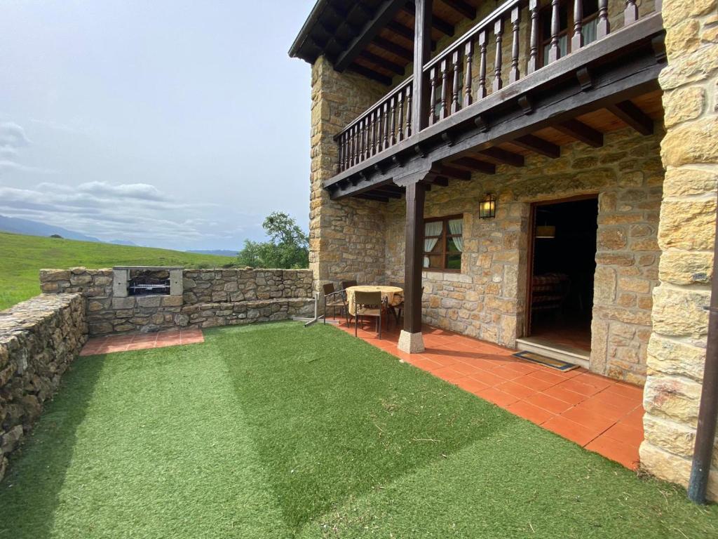 un patio di una casa in pietra con prato di La Helguera Vivienda Vacacional a Villanueva