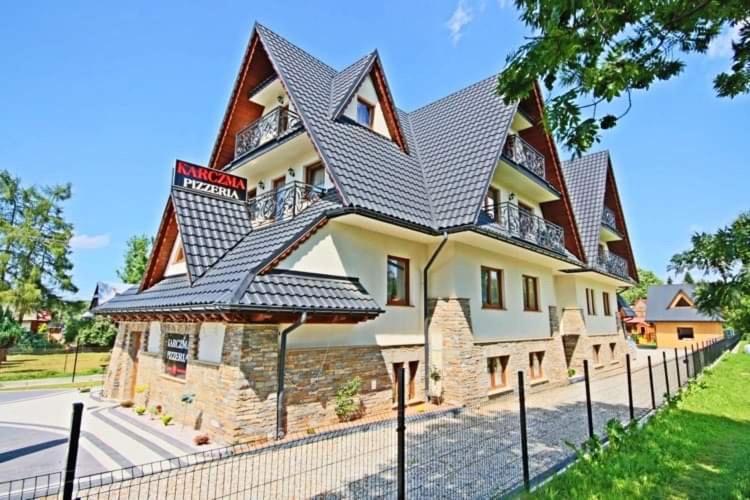 a large house with a gambrel roof at Pokoje u Wojtanka-zniżki na termy in Białka Tatrzańska