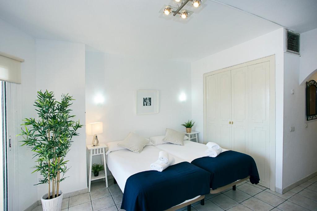 トレモリノスにあるMONKÓ BAOBABの白いベッドルーム(青いシーツを使用した大きな白いベッド付)