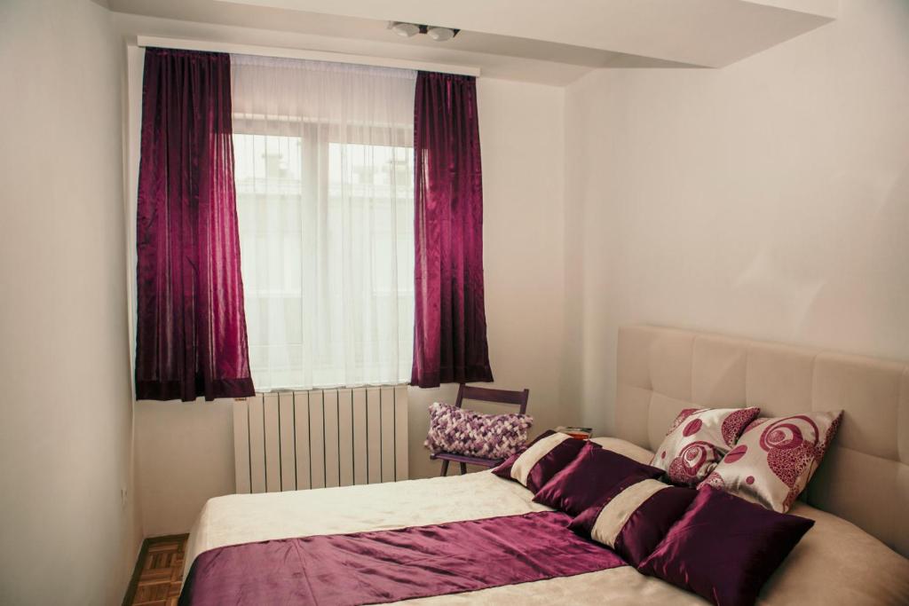 um quarto com uma cama e uma janela com cortinas vermelhas em Ugodan smještaj u Sarajevu em Sarajevo