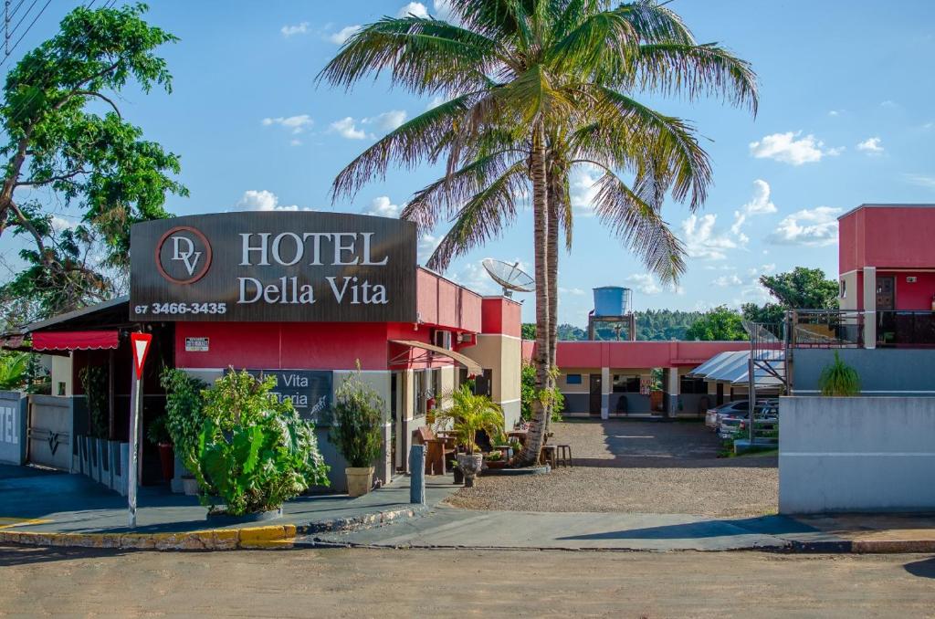 a hotel with a palm tree in front of a building at Hotel Della Vita in Glória de Dourados