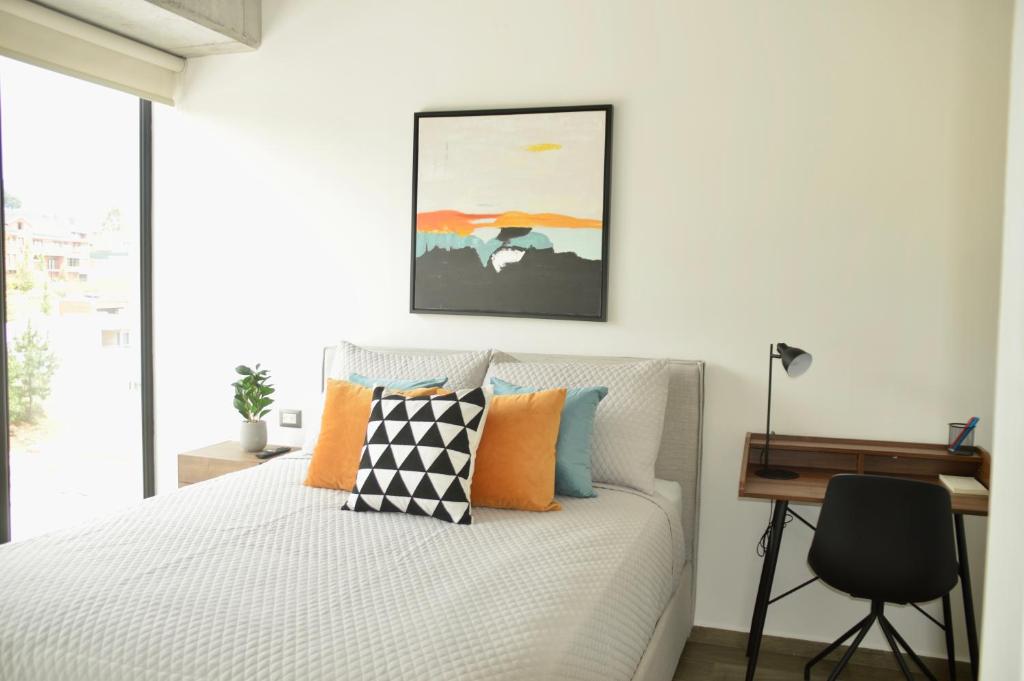 1 dormitorio con cama con almohadas de color naranja y escritorio en Cozy Stays Cayala Apartments 5 en Guatemala