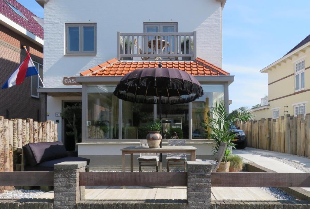 a patio with a table and an umbrella in front of a house at Casa duna close to the beach, city centre, dunes and parking area in Zandvoort