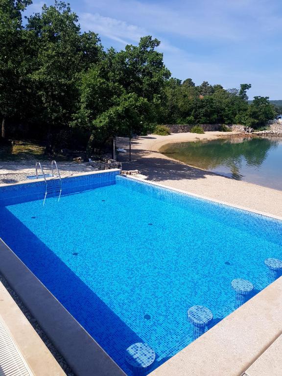 a large blue swimming pool next to a body of water at Krk Mobile Homes in Klimno