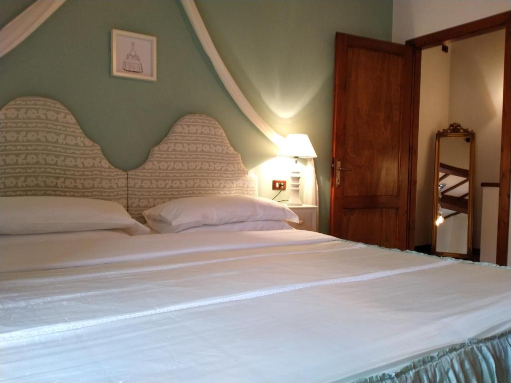 a bedroom with a large white bed with a large headboard at Small lovely home in Pienza in Pienza