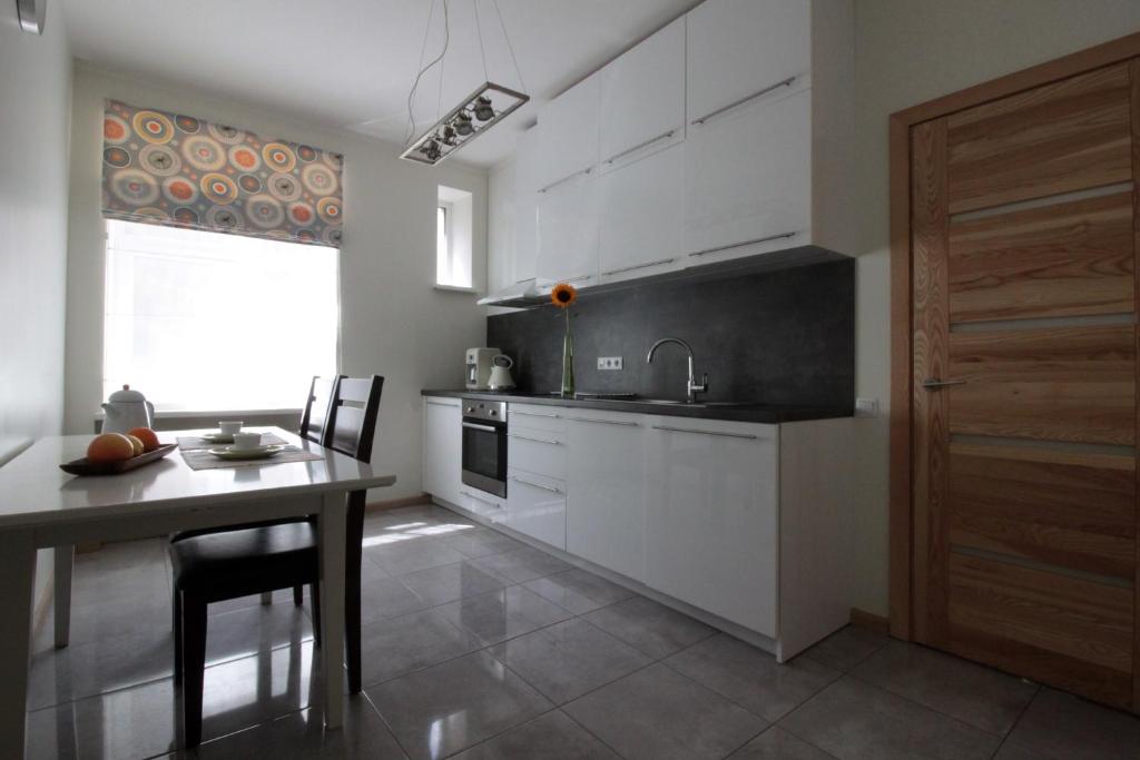 cocina con armarios blancos, mesa y ventana en Modern Cozy 1BR apartment in Quiet center of Riga en Riga