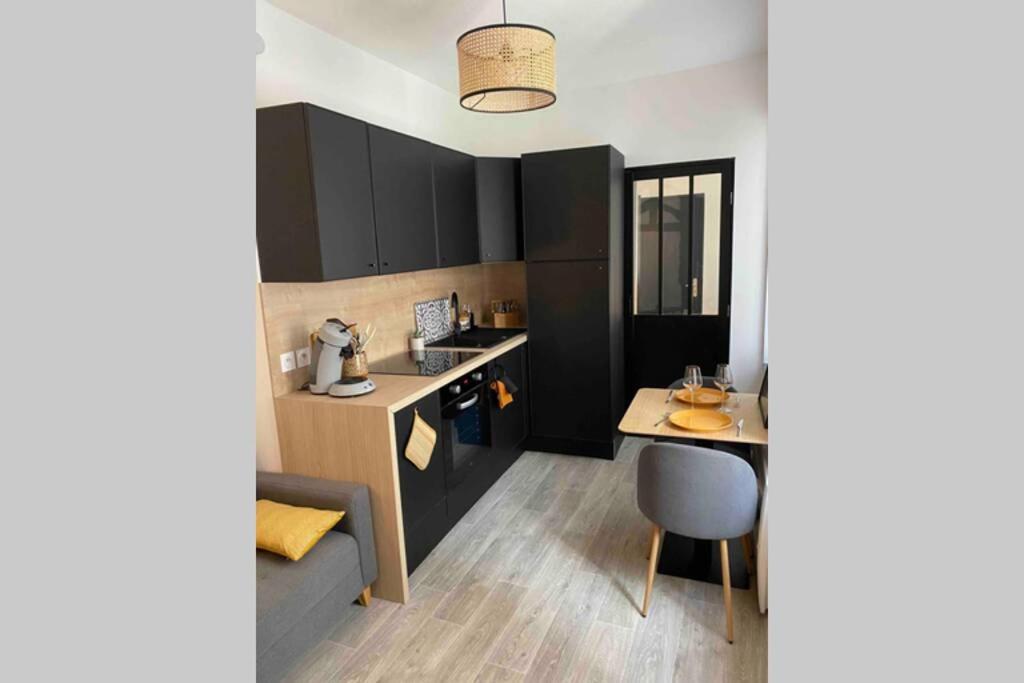 a kitchen with black cabinets and a table and a chair at Appartement centre de Moulins in Moulins
