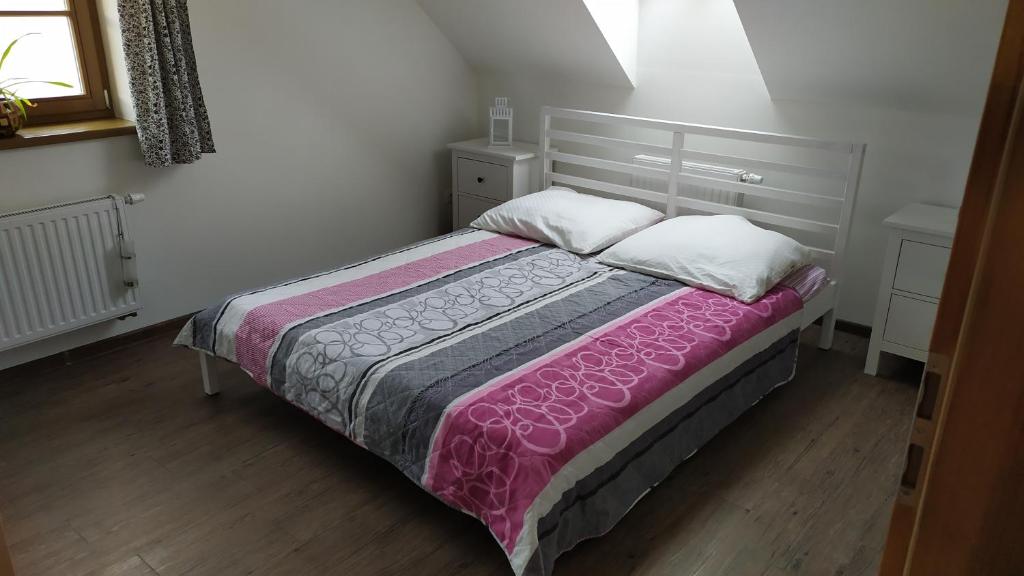 een slaapkamer met een bed met een roze deken en witte kussens bij Loučná in Hrádek nad Nisou