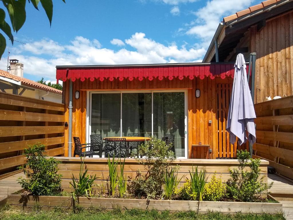 a house with a patio with a table and an umbrella at L Escale Tranquille in Andernos-les-Bains