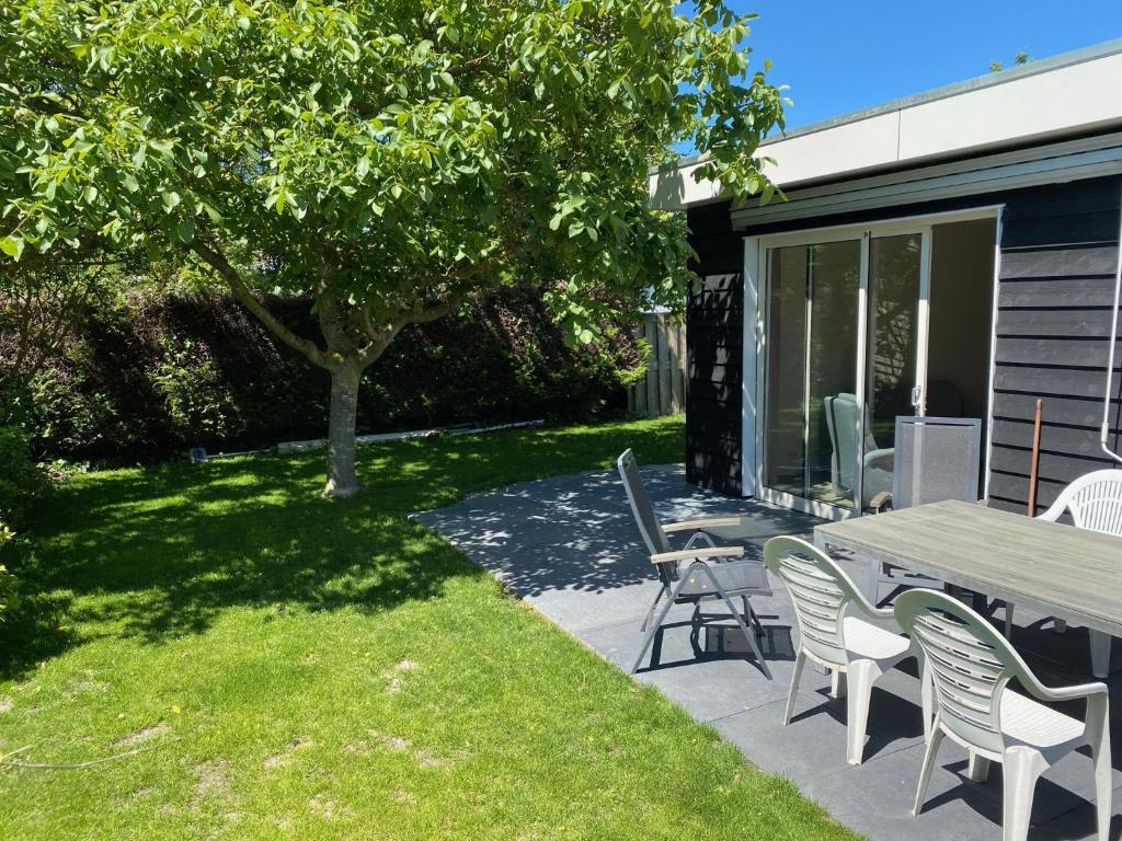 een patio met een tafel en stoelen en een boom bij House in a quiet location in Zeeland 2 in Bruinisse