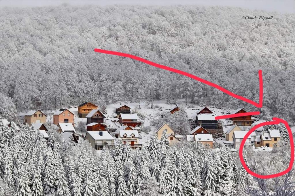 Una flecha roja apuntando a un pueblo en la nieve en maison forêt d'Aubrac , au coeur de la nature, en Prades-dʼAubrac