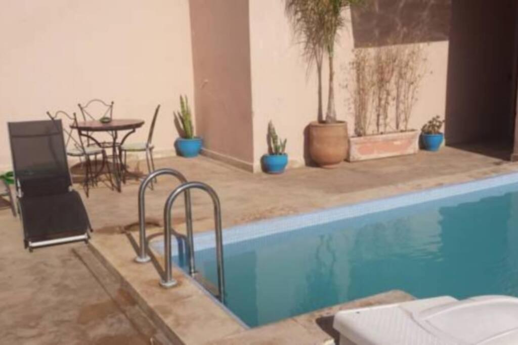 una piscina con mesa, sillas y plantas en Les terrasses de Gueliz, en Marrakech