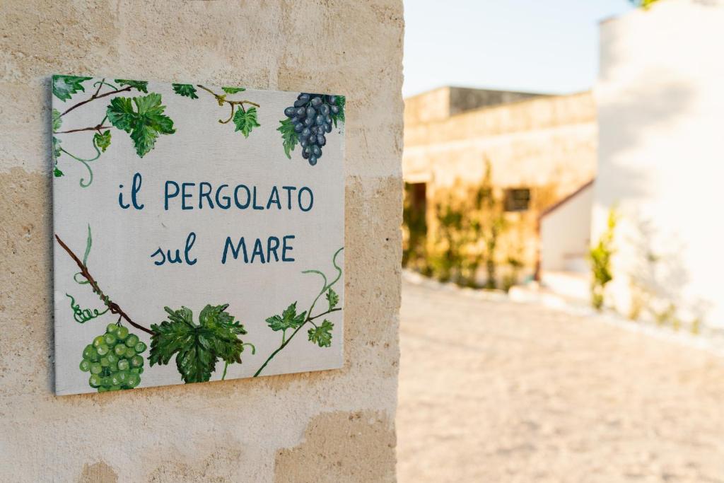 un panneau sur un mur avec une bande de raisins dans l'établissement Il pergolato sul mare, à Monopoli