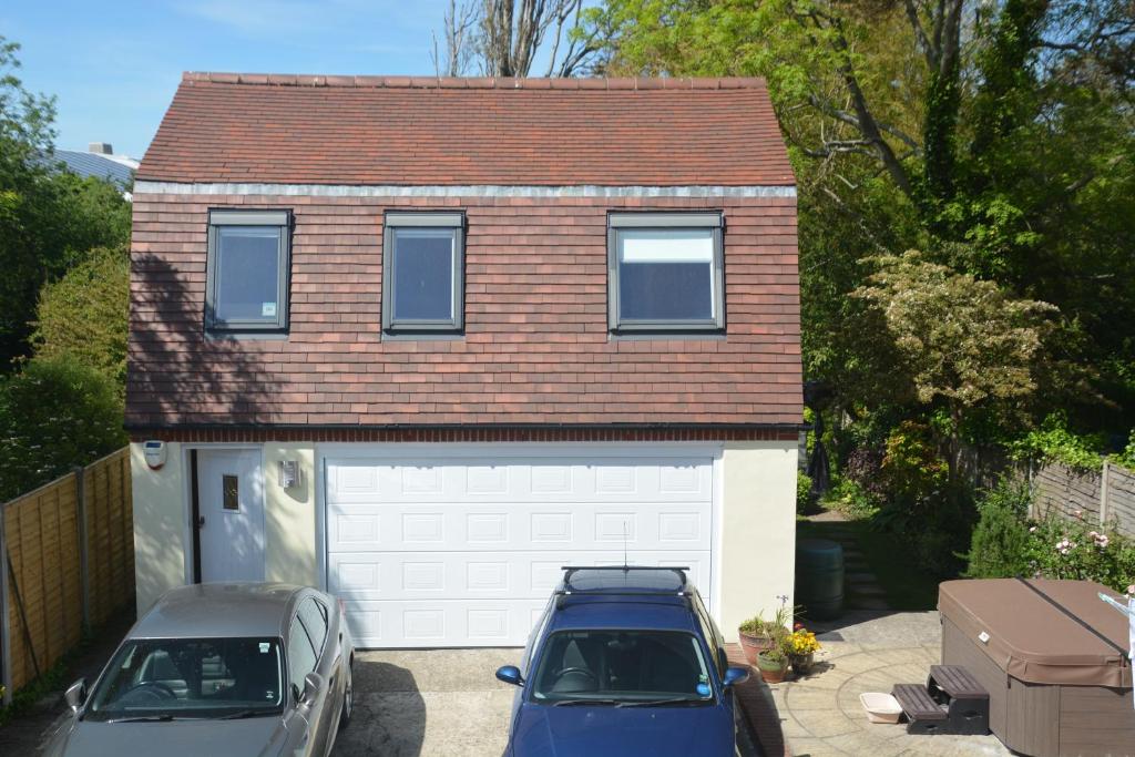 a garage with two cars parked in front of a house at The Garrett in Melcombe Regis