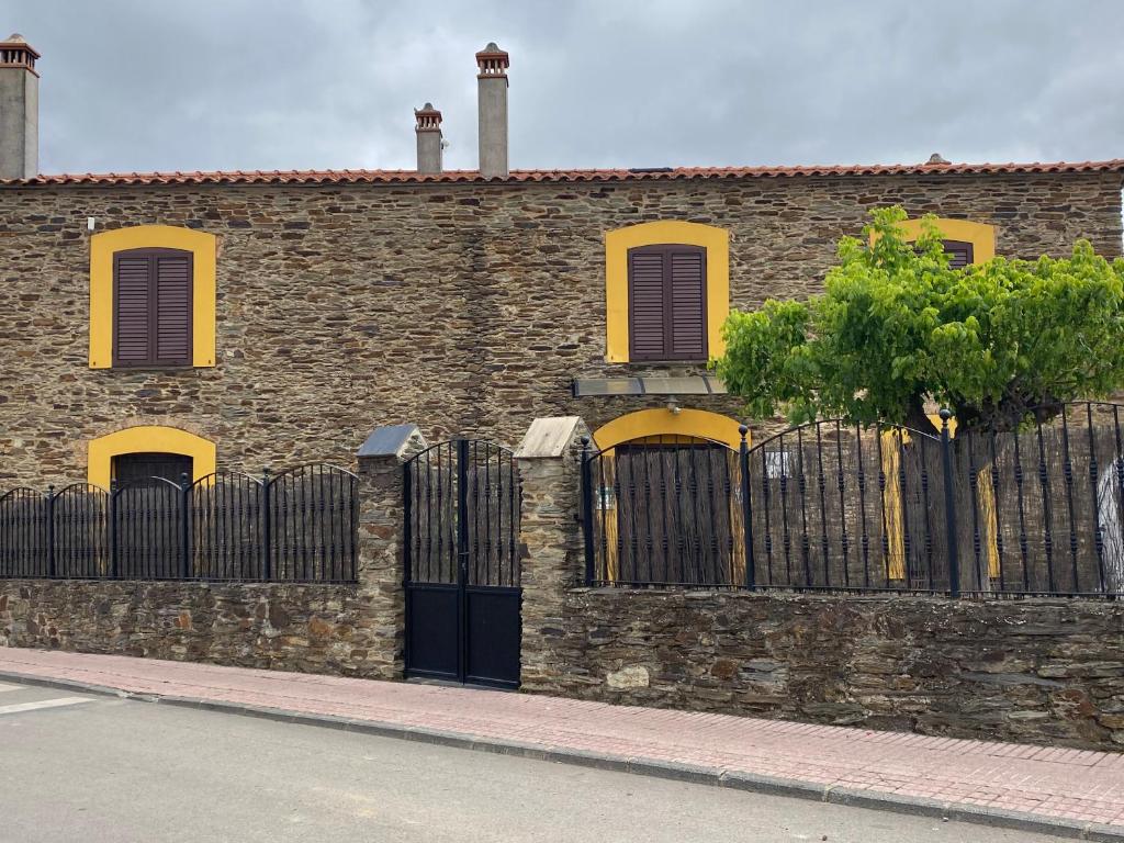 a brick building with a fence and a tree at La Casa Grande de Adolfo in La Codosera
