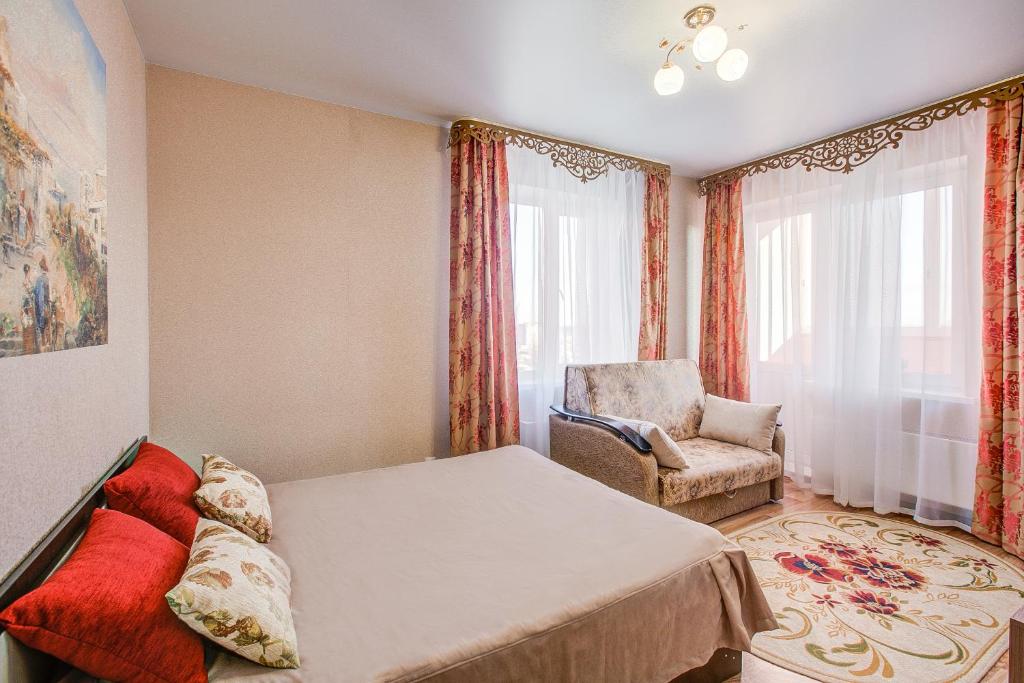 um quarto com uma cama, uma cadeira e uma janela em Apartment on Leninskiy Prospekt em Voronezh