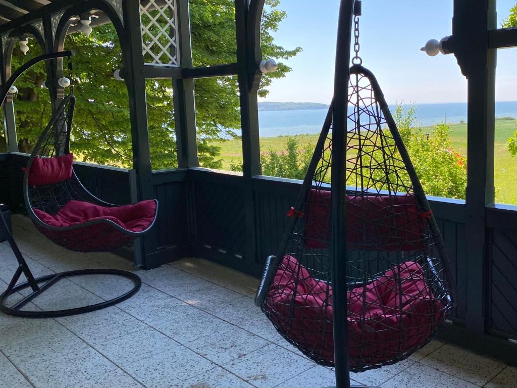 two swings on a porch with a view of the ocean at Ferienwohnung in der Brennerei Mönchgut in Middelhagen