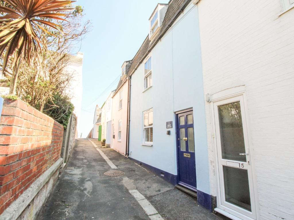 a row of white buildings with blue doors on a street at Firkin Cottage in Weymouth