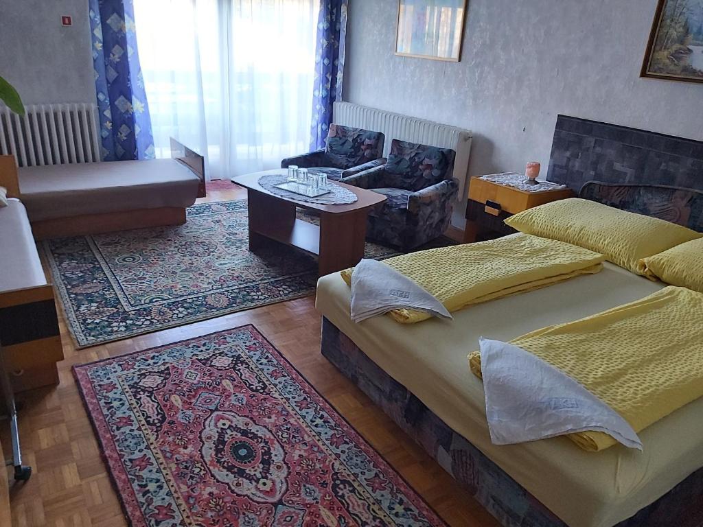 a bedroom with two beds and a living room at OPEN Vendégház in Sopron