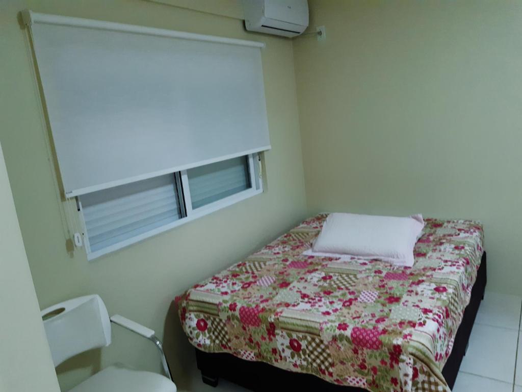 Habitación pequeña con cama y ventana en Apto JK Universitário - Express, en Santa Cruz do Sul
