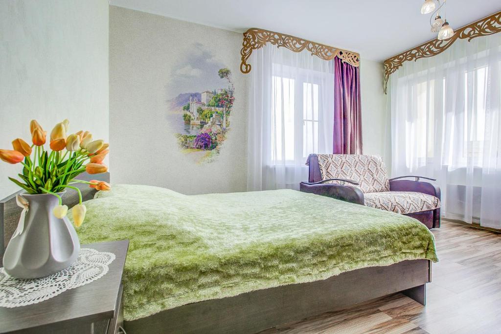 um quarto com uma cama verde e um vaso de flores em Apartment on Leninskaya em Voronezh