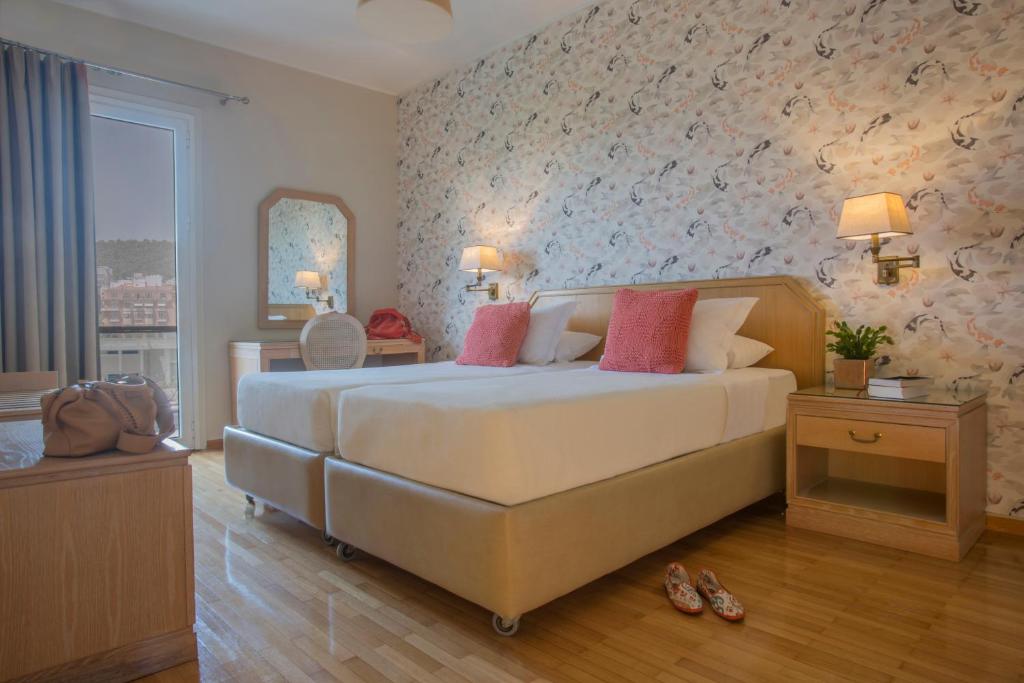 1 dormitorio con 1 cama blanca grande con almohadas rosas en Delice Hotel - Family Apartments en Atenas