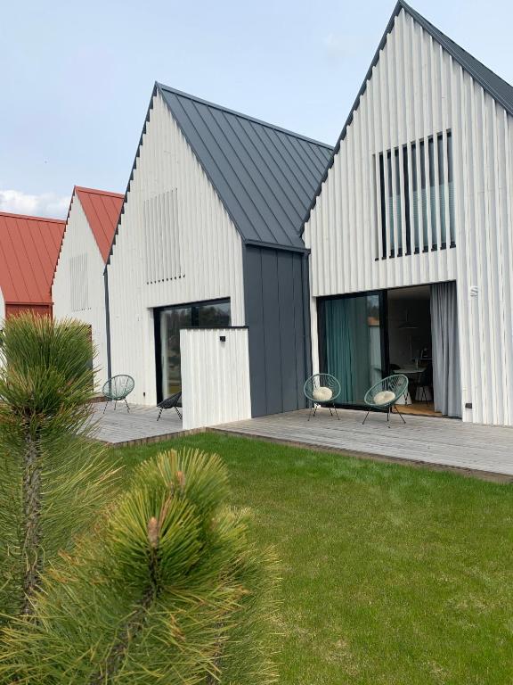 a black and white building with two chairs in a yard at Aurora apartments in Palanga