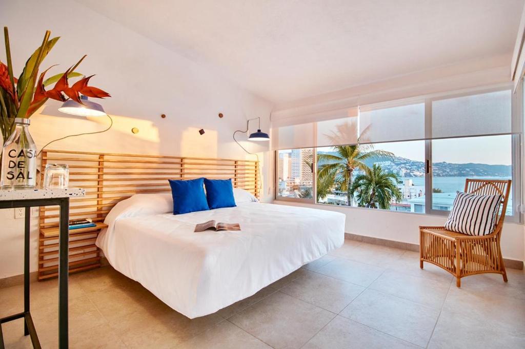 a bedroom with a large bed with blue pillows at Hotel Casa de sal in Acapulco