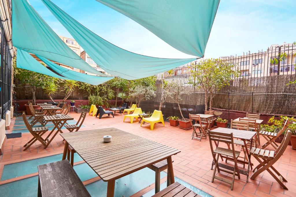 un patio con mesas, sillas y una sombrilla azul en ELLA Guest House Barcelona, en Barcelona