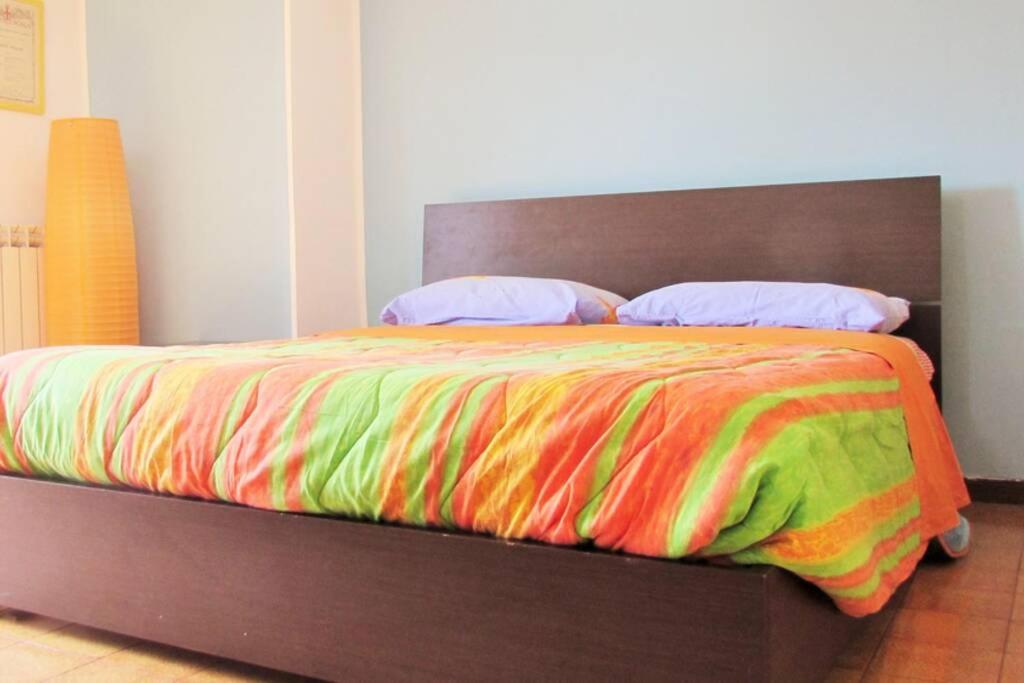 un letto con coperta colorata e cuscini sopra di Sky Sunset a Milano