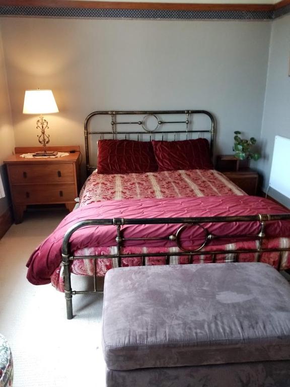 a bedroom with a bed with a red comforter at Manakau House The Old Manakau Hotel 1920 in Manakau