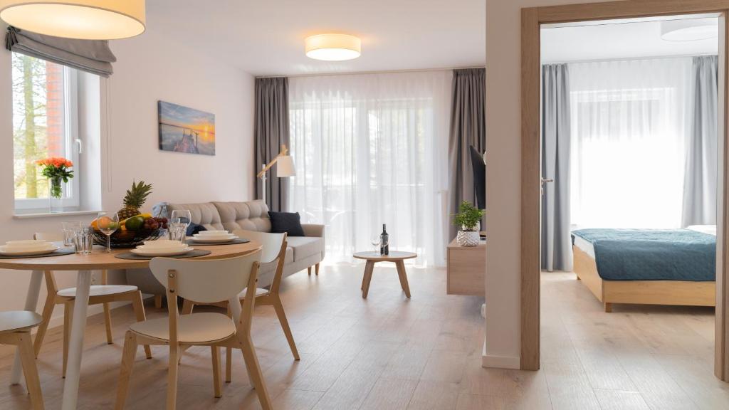 een woonkamer en eetkamer met een tafel en een slaapkamer bij Apartamenty BALTIVIA Olimpijska 2 in Mielno