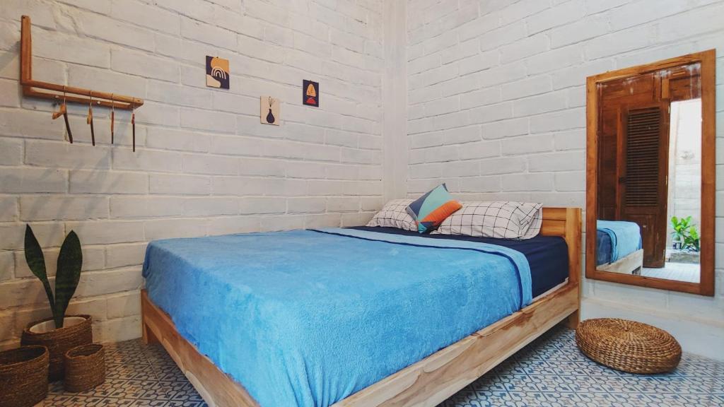 Schlafzimmer mit einem Bett mit blauer Bettwäsche und einem Spiegel in der Unterkunft KALINDA HOMEY in Karimunjawa