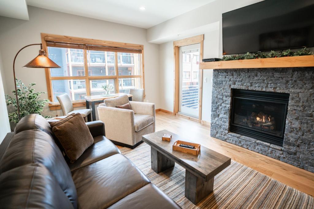 sala de estar con sofá y chimenea en Spring Creek Luxury Queen Suite at White Spruce Lodge, en Canmore