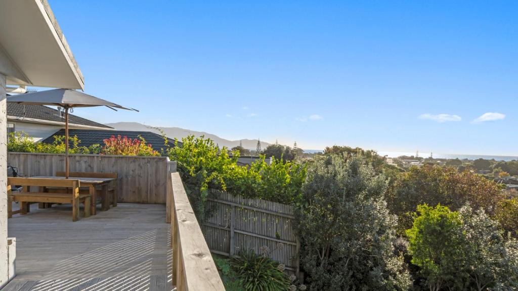 a patio with a wooden table and a wooden fence at Kapiti Views - Waikanae Beach Holiday Home in Waikanae