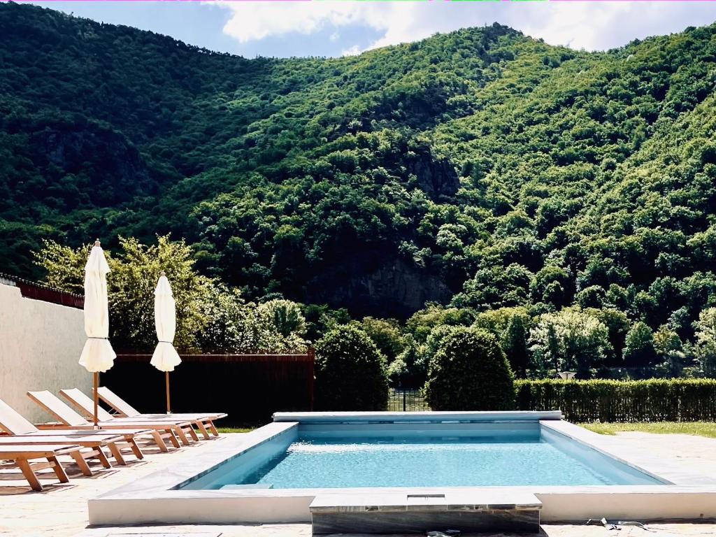 a swimming pool with two chairs and a mountain at Renaissancehof Wieser Wachau in Wösendorf