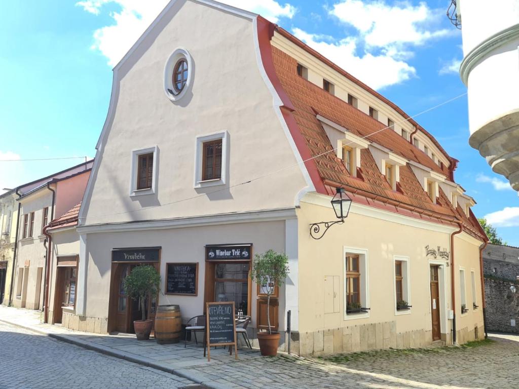 a white building with a red roof on a street at Penzion Hradební in Telč