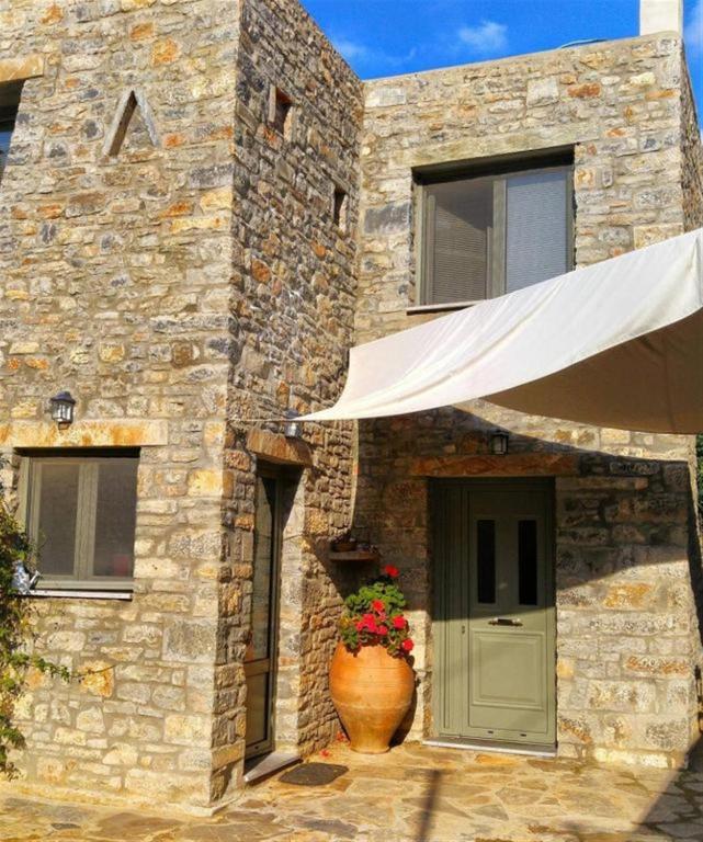 a stone house with a green door and a vase with flowers at Casa di Pietra in Neápolis
