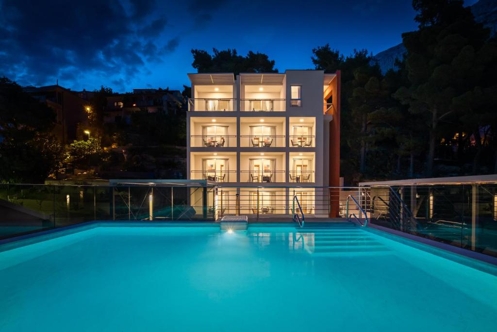 a hotel with a swimming pool in front of a building at Noemia Apartments in Baška Voda