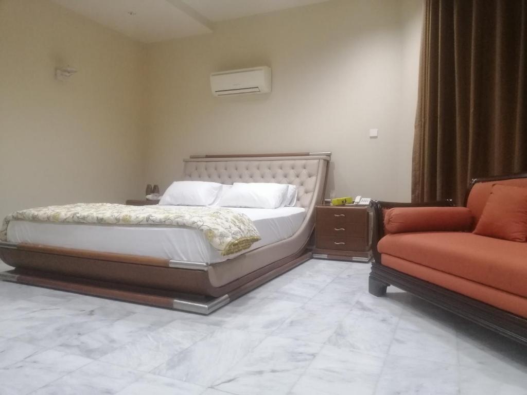 ein Schlafzimmer mit einem Bett, einem Stuhl und einem Sofa in der Unterkunft HOTEL STATE RESIDENCY in Bahawalpur