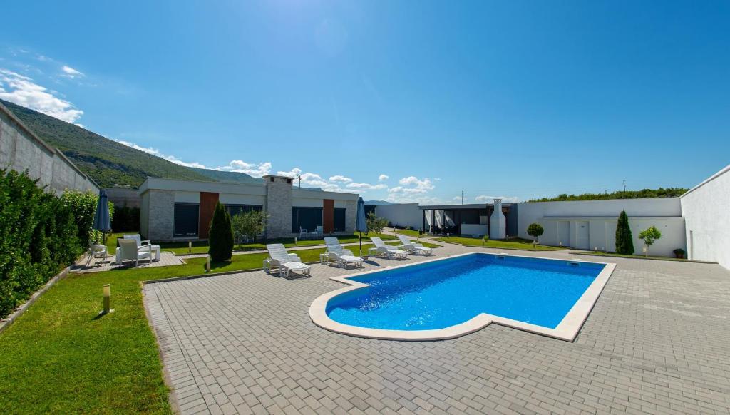 einen Pool in einem Garten mit Stühlen und einem Gebäude in der Unterkunft Luxury Villa in Mostar in Mostar