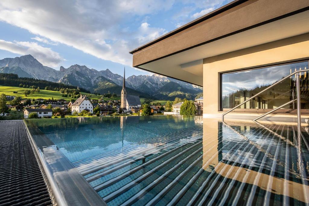 a house with a swimming pool with a view of mountains at die HOCHKÖNIGIN - Mountain Resort in Maria Alm am Steinernen Meer