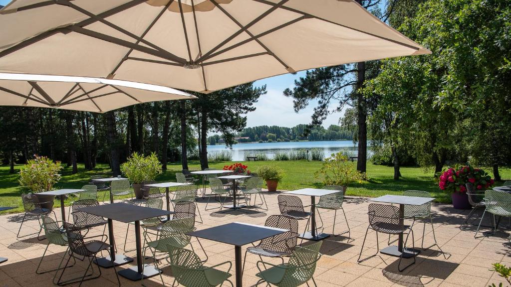 een groep tafels en stoelen met parasols bij Best Western Hotel du Lac Dunkerque- Restaurant ouvert 7/7 midi et soir in Armbouts-Cappel